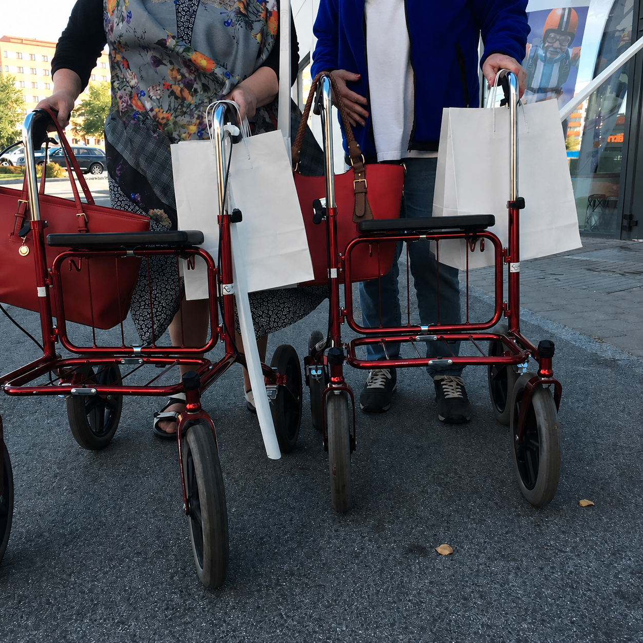 Två äldre personer med rollatorer på väg hem efter ett besök